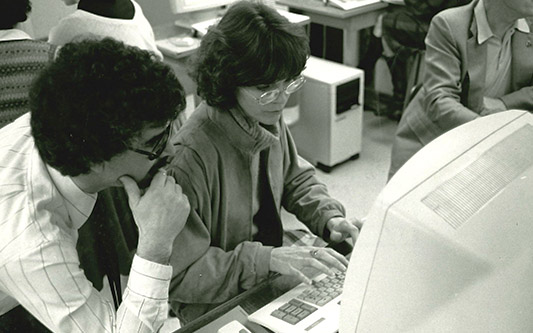 black and white photo of student and a professor looking at a desktop computer