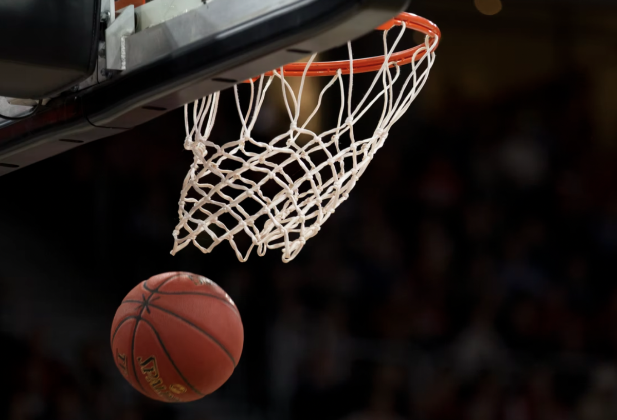 below a basketball net with a ball going in the basket