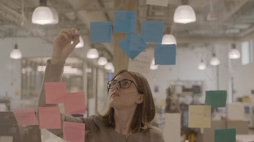 Student working with sticky notes on glass wall
