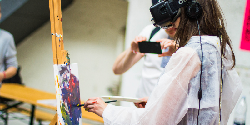 person wearing a VR headset while painting on a canvas