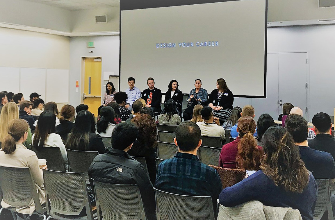 Six panelists speaking to a full room of students