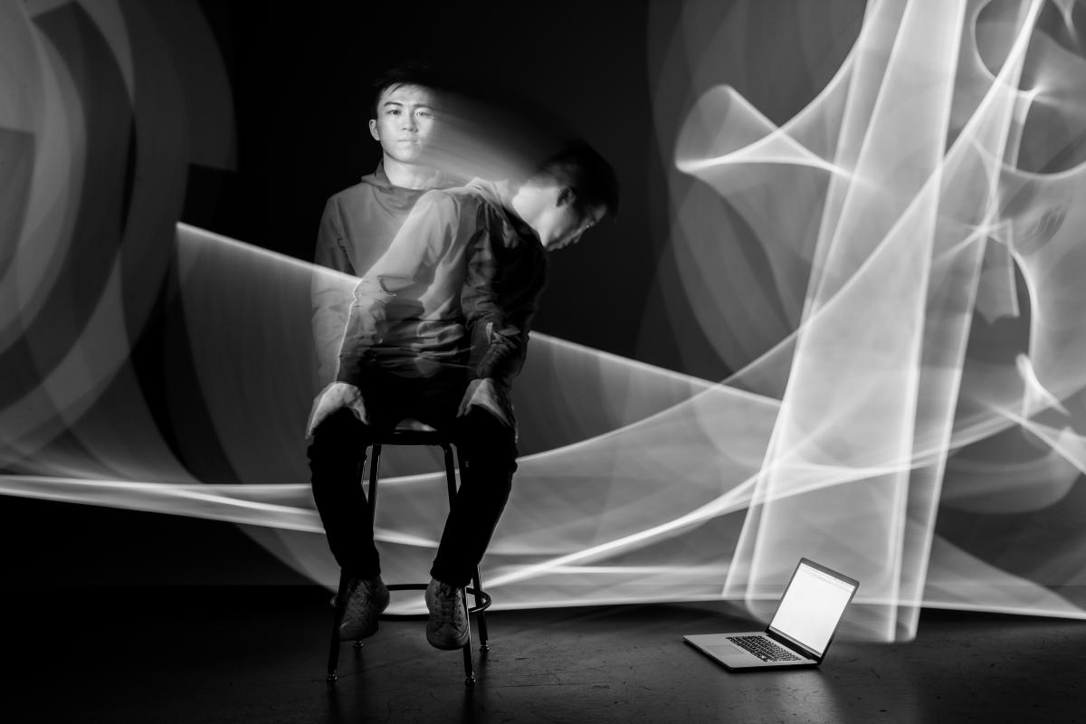 stylized photo of blurry student looking between the camera and a computer