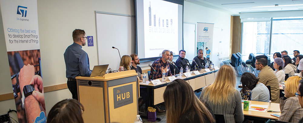 panelists at the front of the room in the HUB, with moderator Tyler Fox