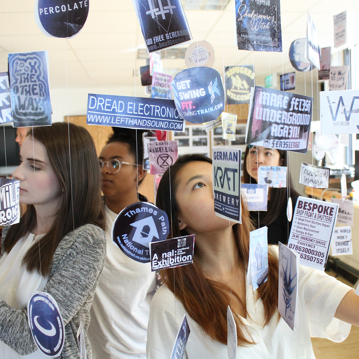 Students standing among signage and stickers hanging from the ceiling by strings