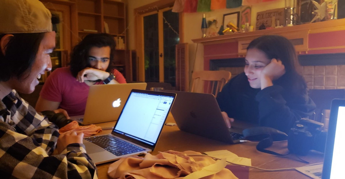 Students gathered around a table on laptops