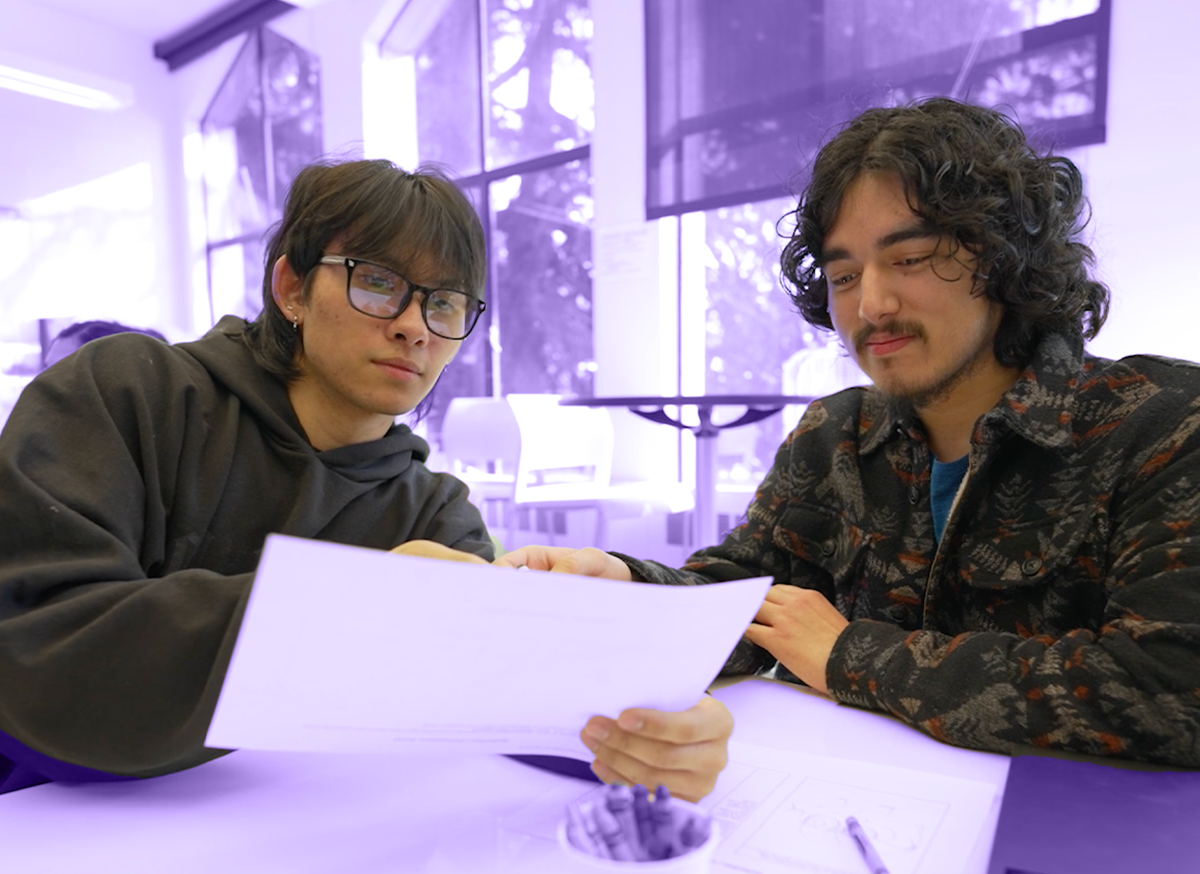 Two students look at a piece of paper in an HCDE classroom