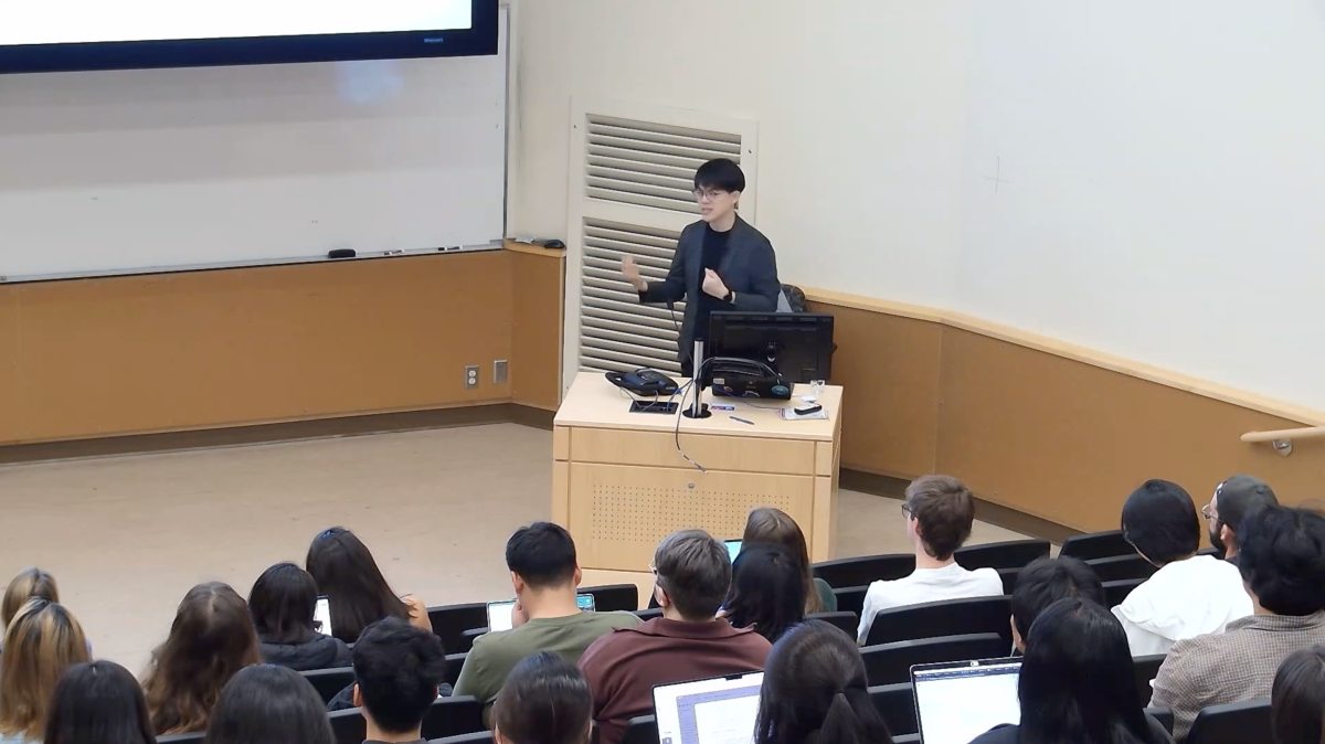 A person speaks from the podium to the classroom