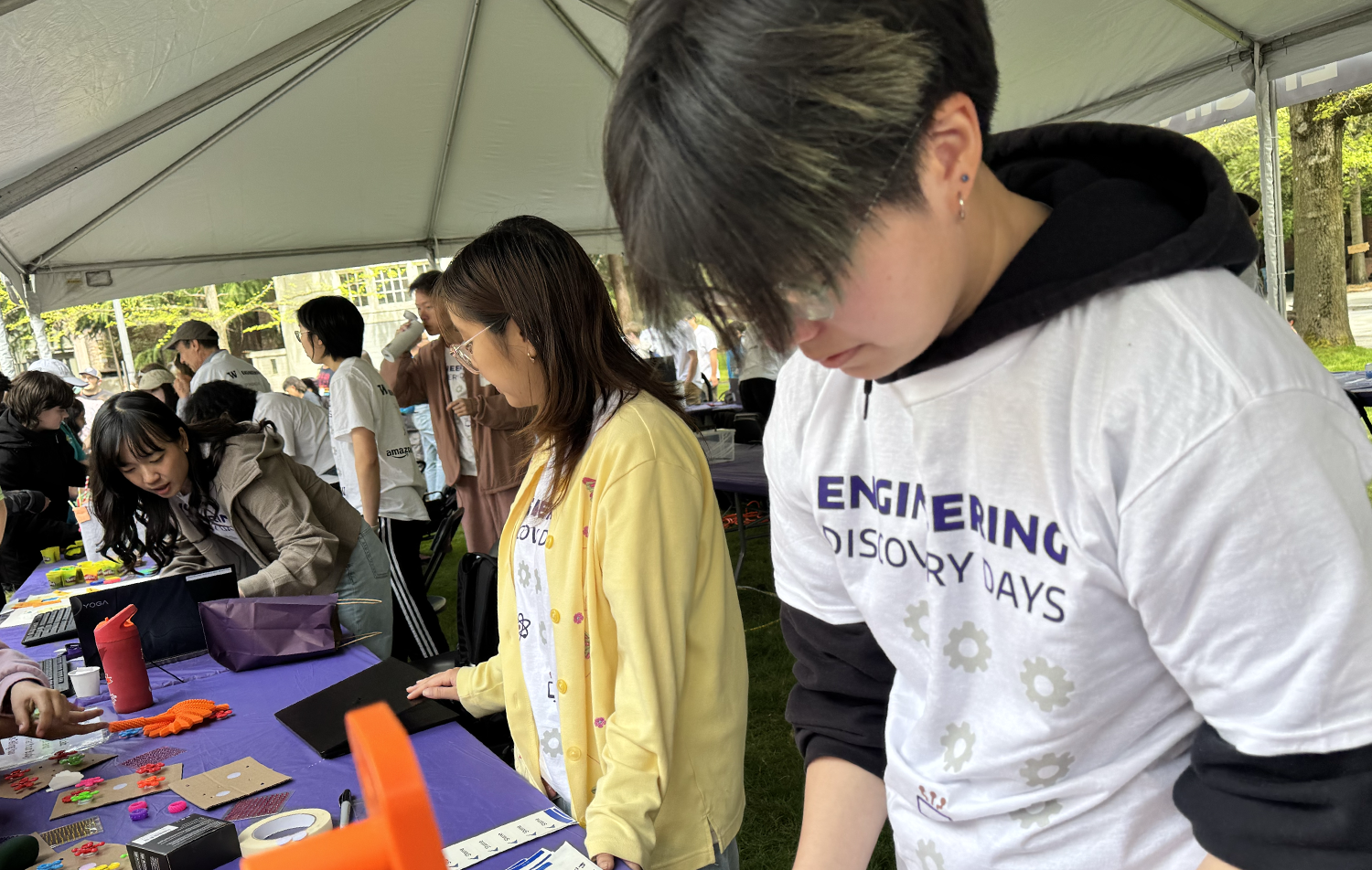 Two students stand behind a table at an HCDE discovery days exhibit