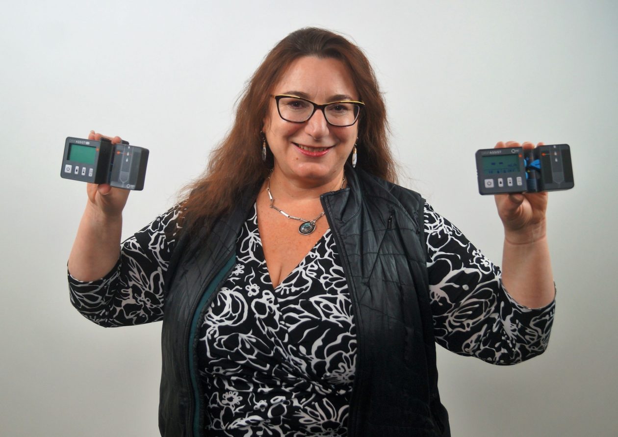 Beth Kolko holds the drip assist device while smiling for the camera