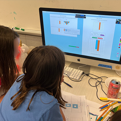 two children play AI Puzzlers on a desktop computer