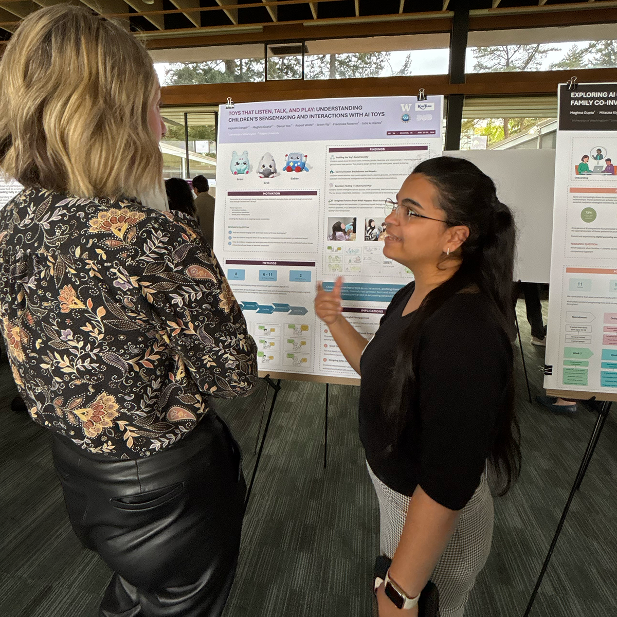 A student stands with their poster talking to attendees