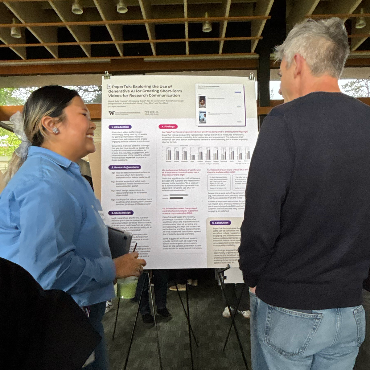A student stands with their poster talking to attendees