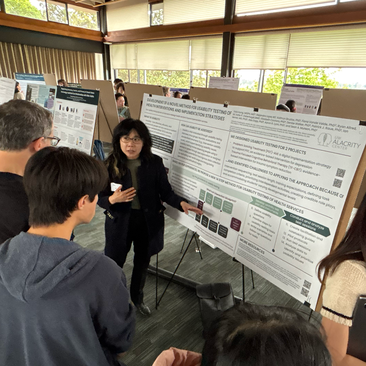 A student stands with their poster talking to attendees