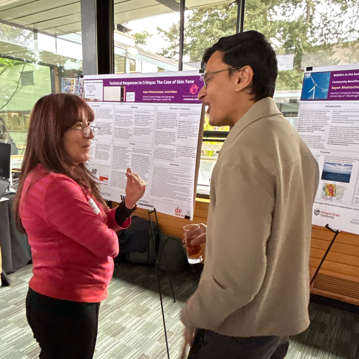 A student stands with their poster talking to attendees