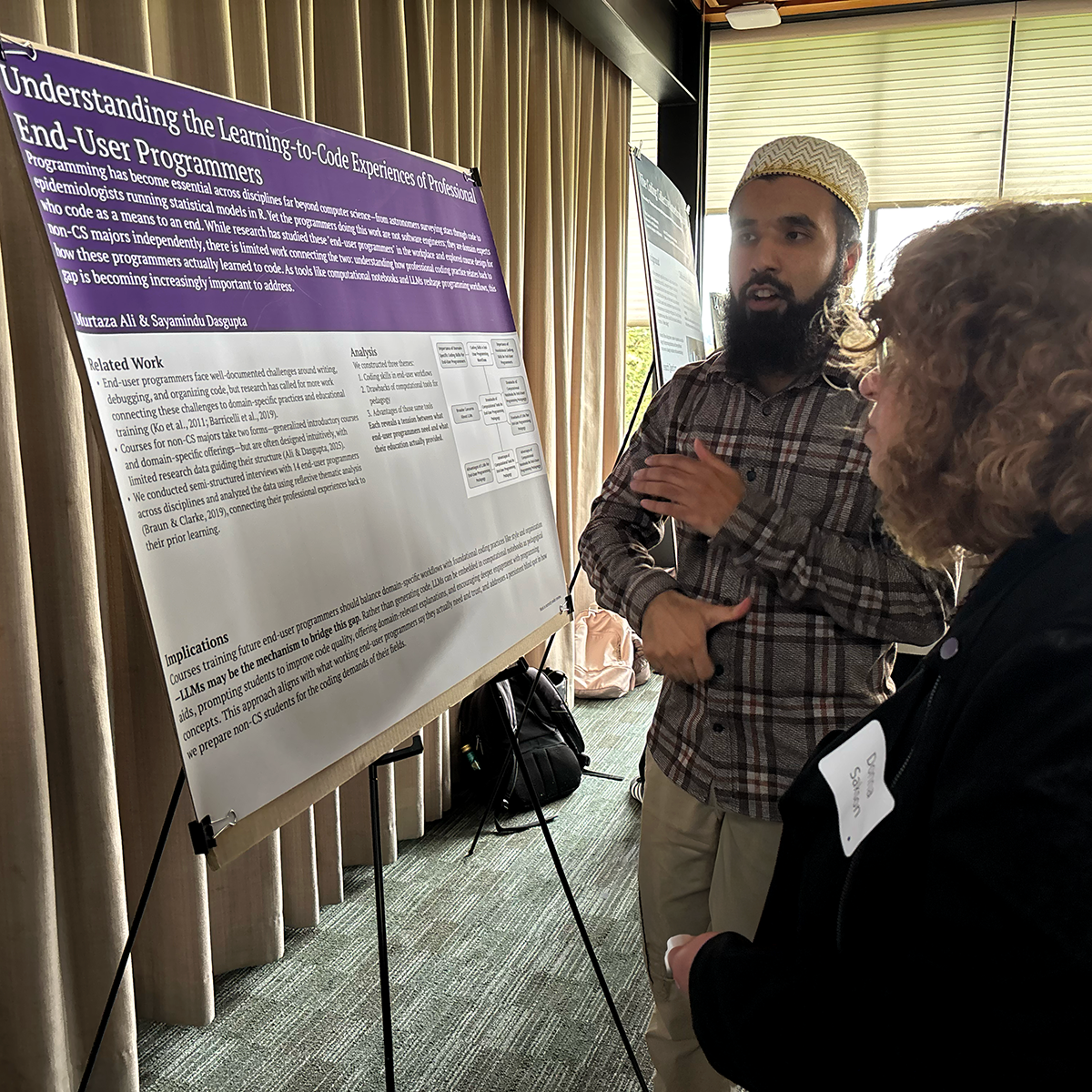 A student stands with their poster talking to attendees