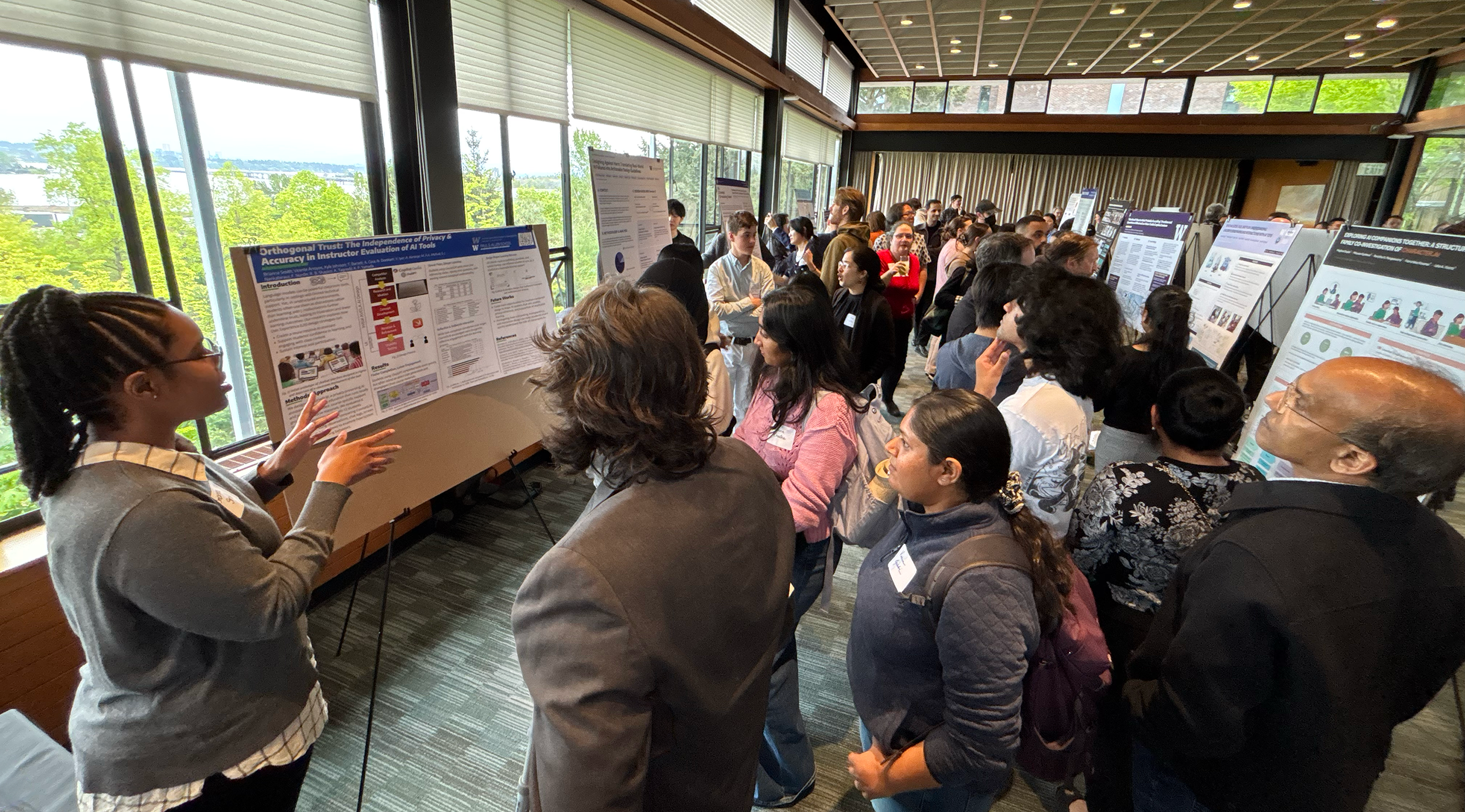 A student presents their poster to a gathering of attendees