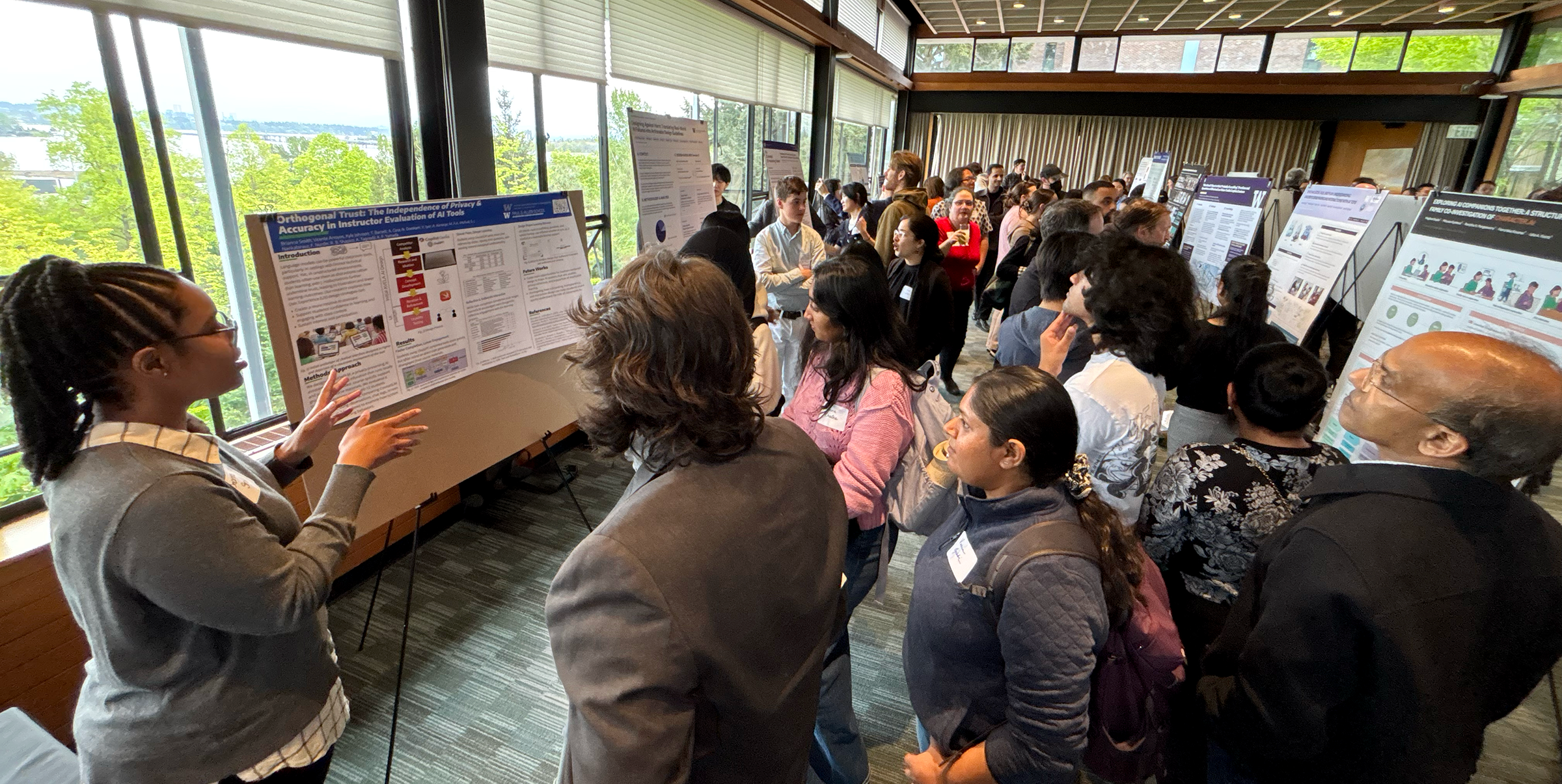 A student presents their poster to a gathering of attendees