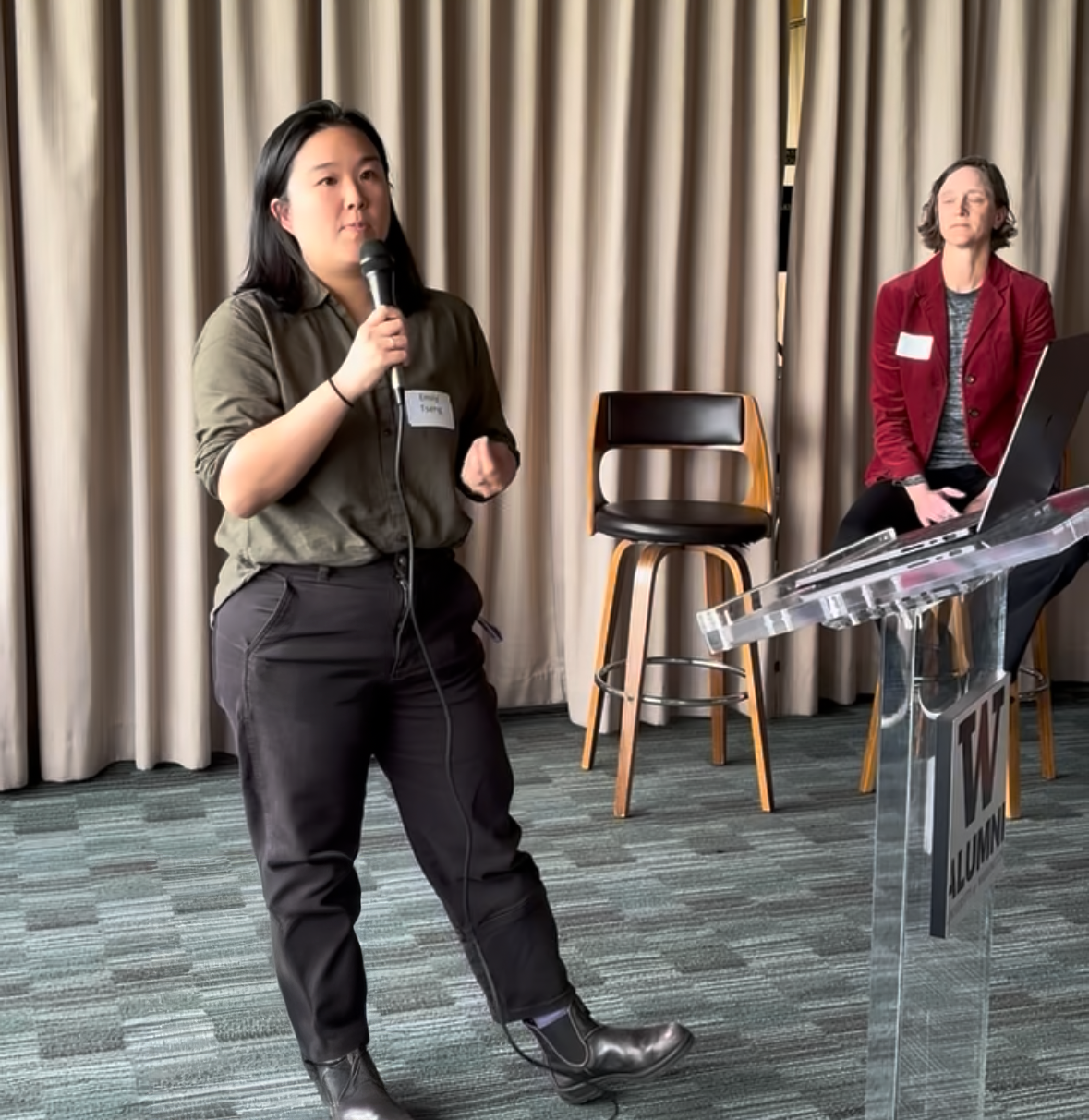 Emily Tseng stands with a microphone speaking to attendees