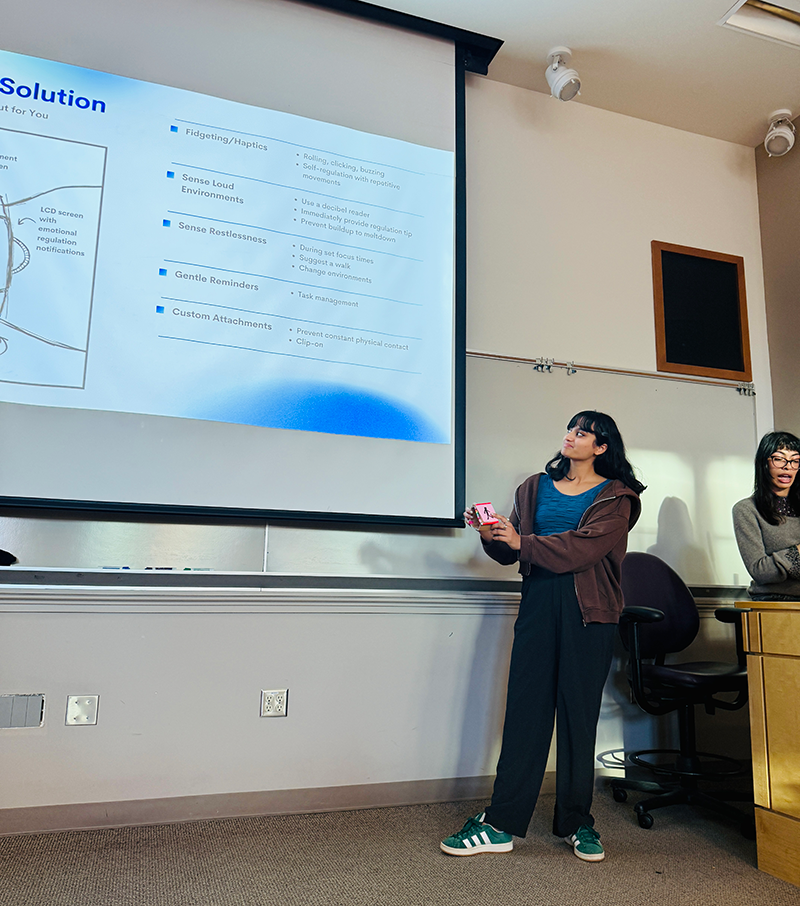 A student presents with a projection screen behind them