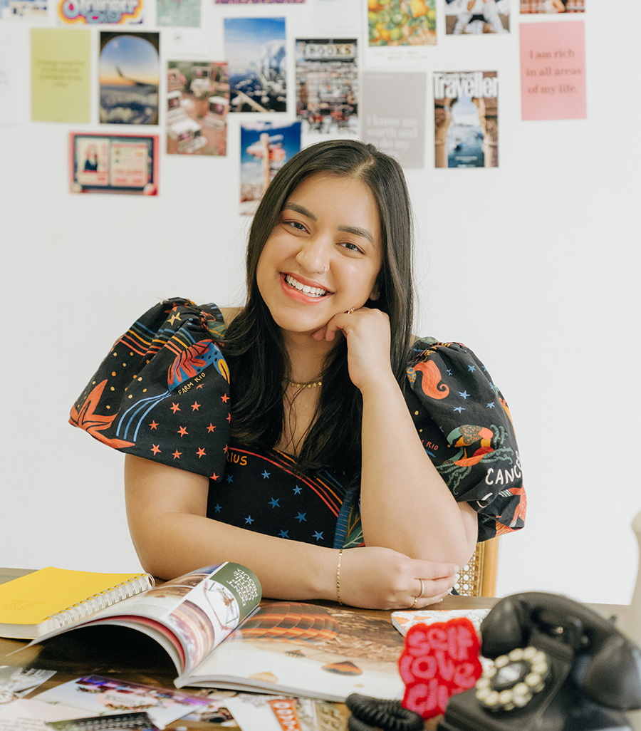 Aleenah sits at a desk while smiling at the camera