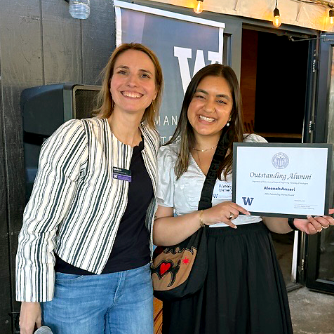 Julie Kientz poses with Aleenah who's holding the award certificate outside at the alumni social