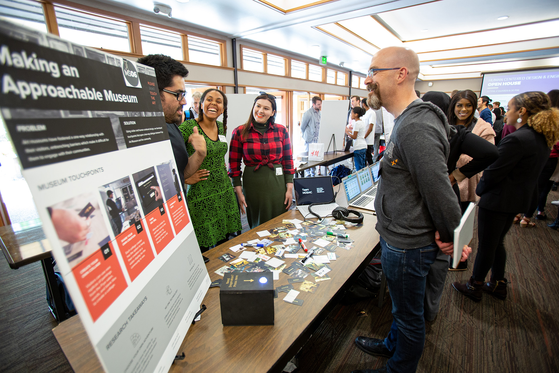 three students stand with their capstone poster titled 'making an approachable museum'