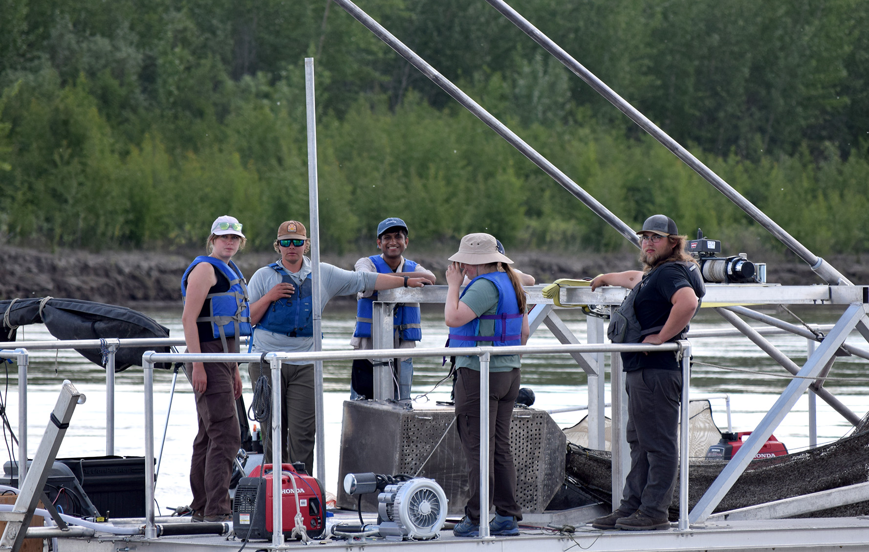 Four HCDE students smile from a research boat on the water