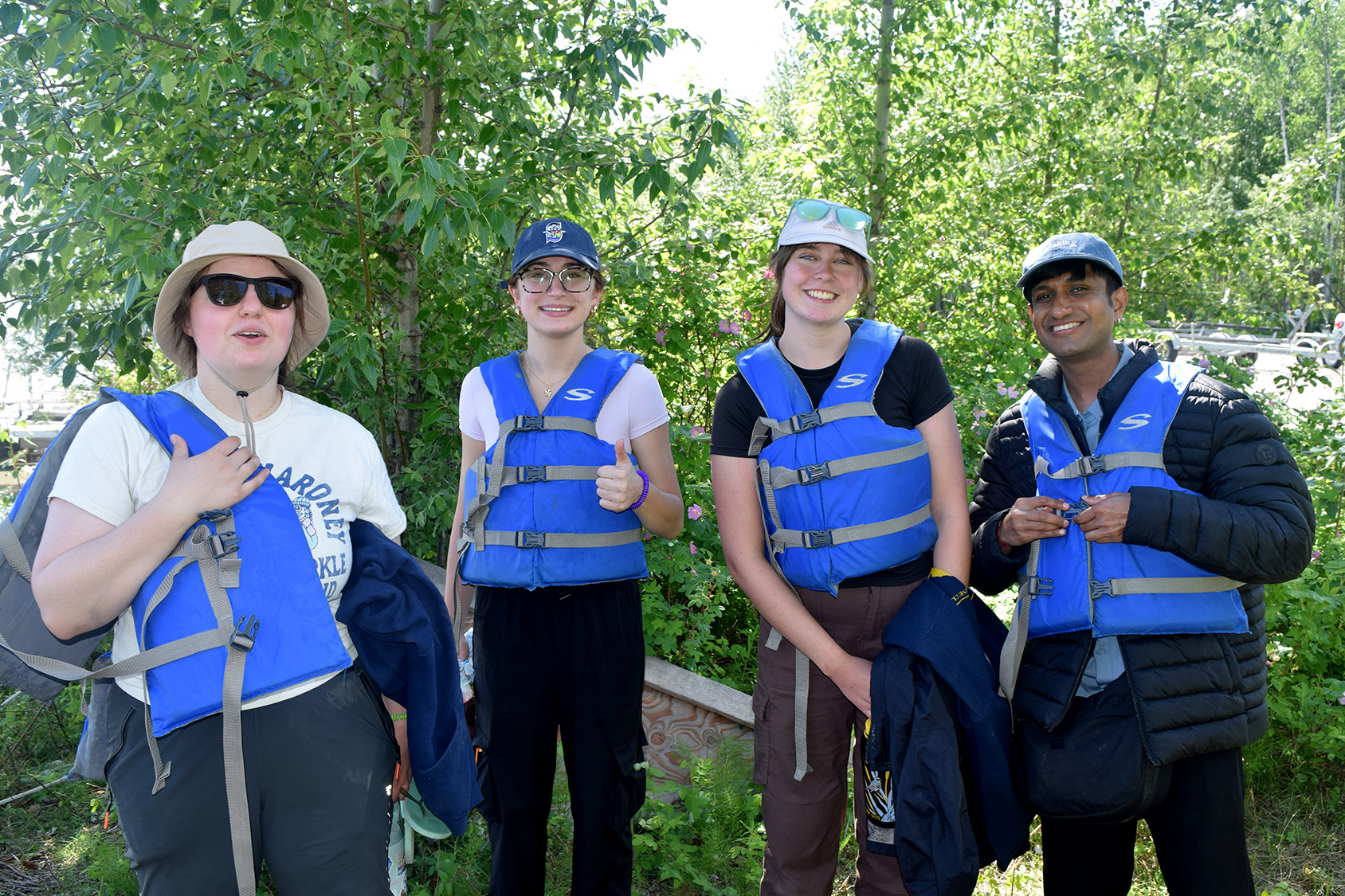 Four students smile wearing life vests in Alaska