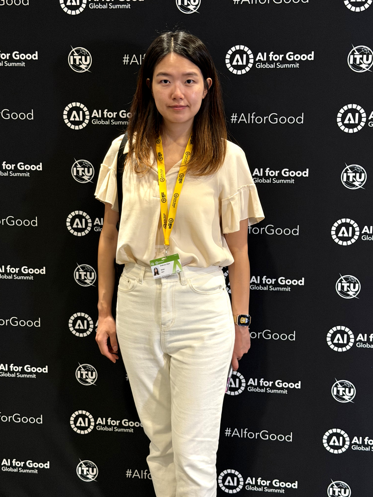 Selah stands in front of AI for Good Summit banner