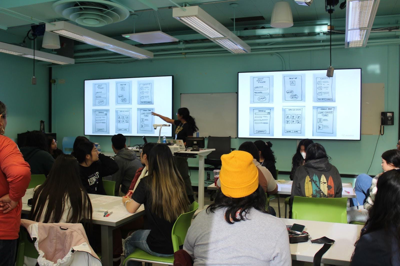 student presenting on screen in front of class full of younger students in HCDE's Sieg Building