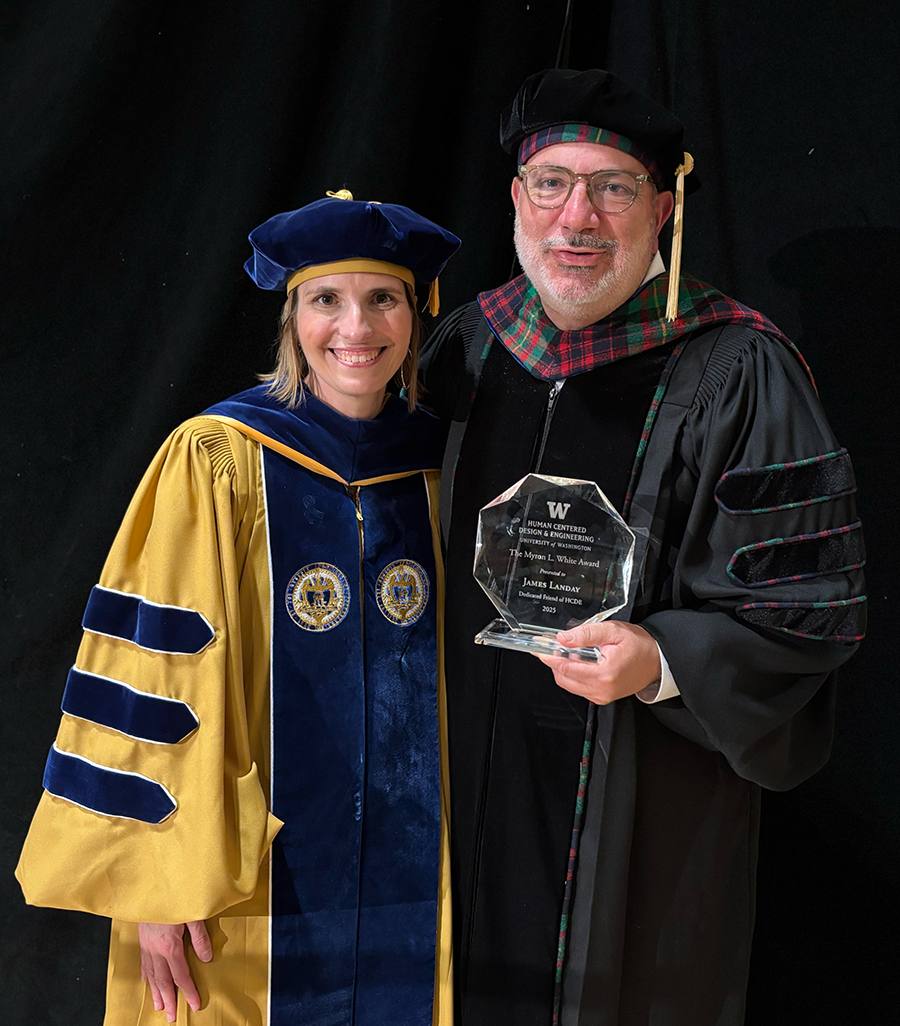 James Landay and Julie Kientz, both wearing regalia, pose with the glass Mikey Award at the HCDE Graduation Ceremnony