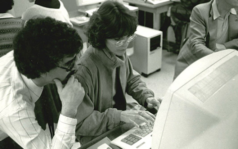 black and white photo of student and a professor looking at a desktop computer