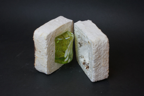 A small green glass sits in a white packing material.
