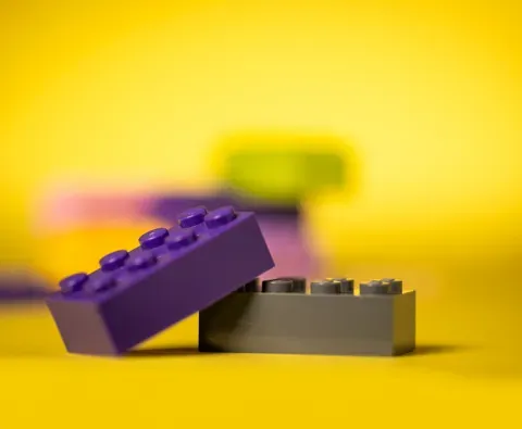 stacked purple lego blocks with yellow background