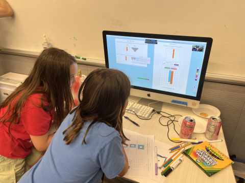 Two students work together testing AI Puzzlers game on a desktop computer