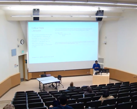 A person speaks in front of a large classroom