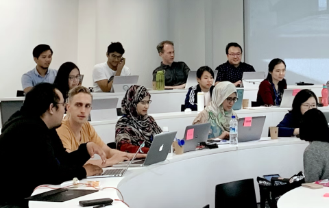 Students working on laptops during a class in a tiered classroom.