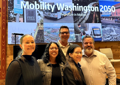 Five project leads stand in front of Mobility Washington 2050 sign