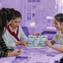 Three students work on a paper prototype of a phone interface