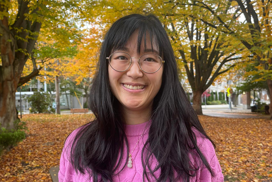 Carolyn Chen standing outside with fall leaves on the ground