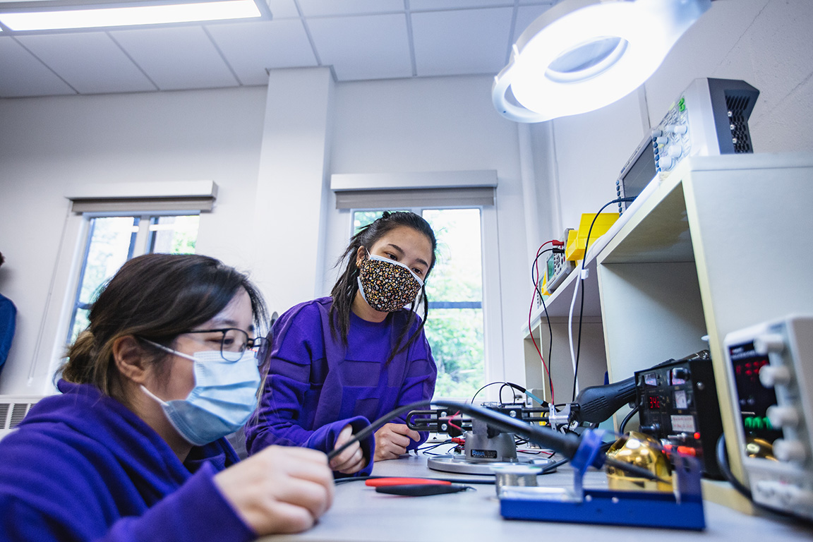 Two women students working with a soldering tool