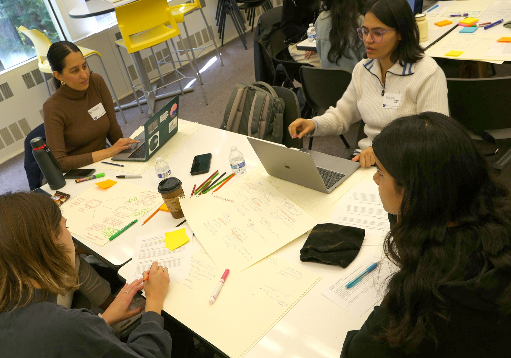 Team of three students working around a table covered with sketches