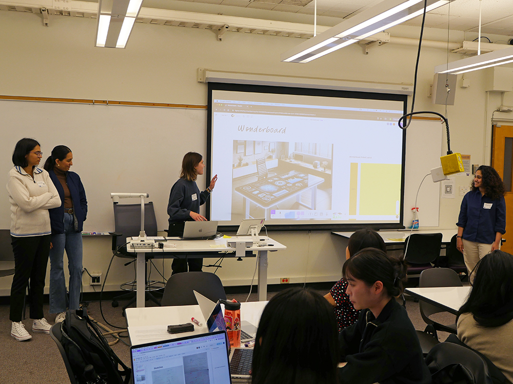 Team of four students presenting their prototype. One student is pointing to the slide that says Wonderboard