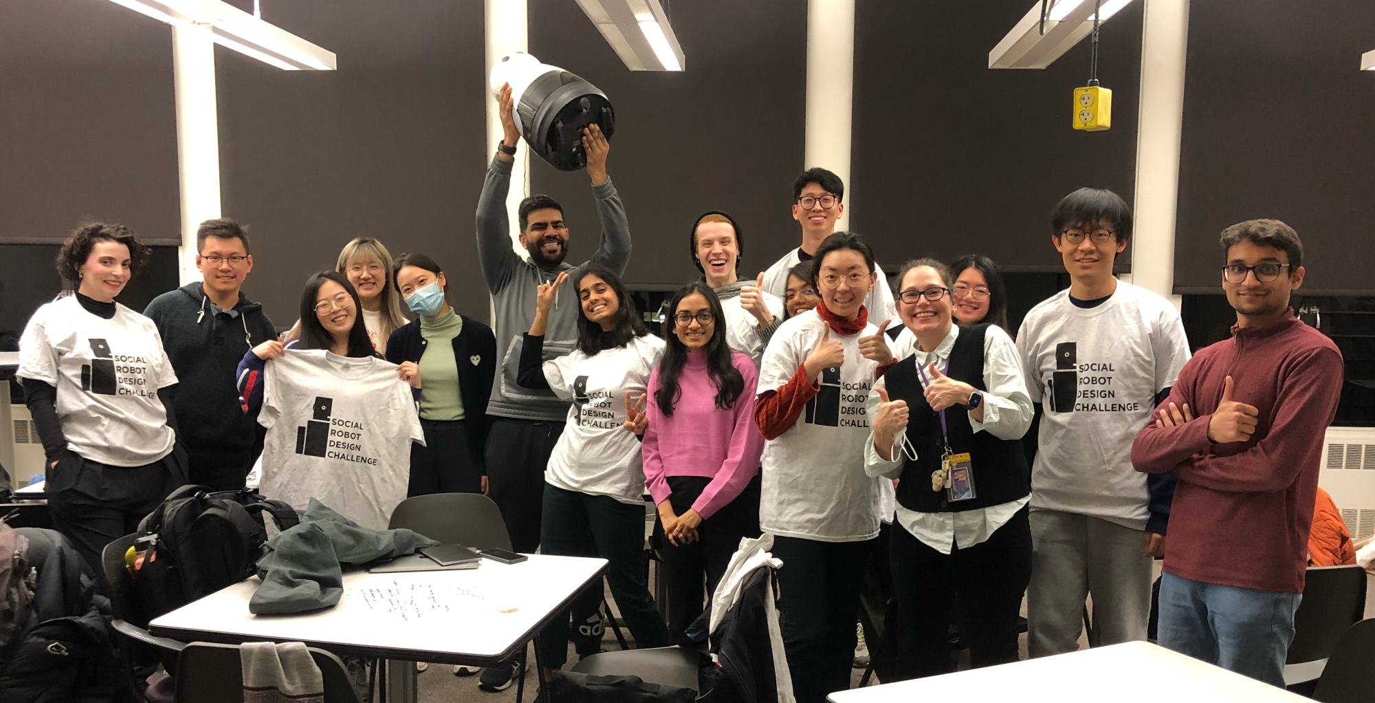 Group photo of Björling and students in the class, some wearing robot t-shirts and some holding robots