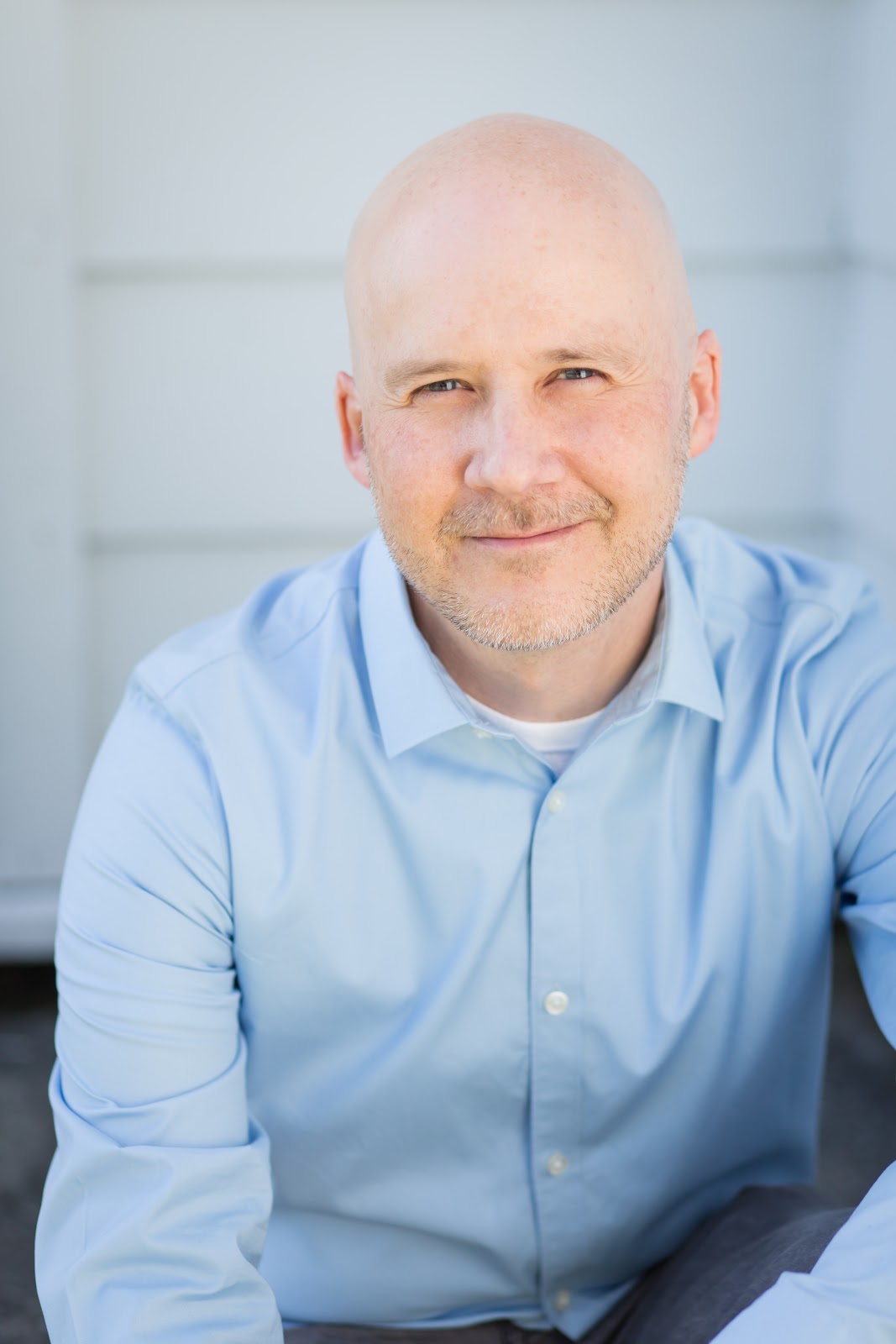 Dr. Jerrod Larson poses in a blue button-up shirt, smiling at the camera