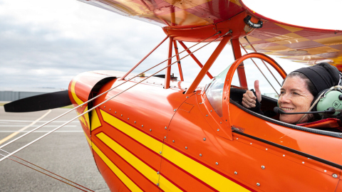 Cecilia giving a thumbs up from the pilot seat in a plane