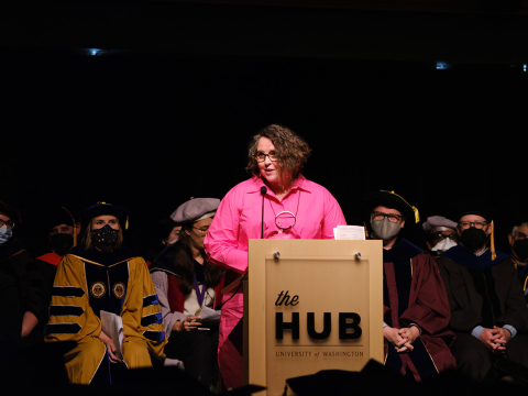 Gail Thynes on stage at the HCDE graduation ceremony with HCDE faculty behind her