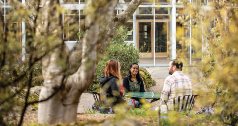 Three people sitting around a table outside