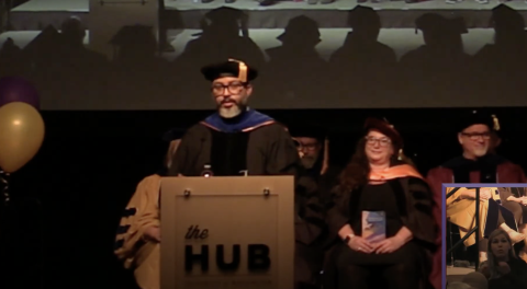 screenshot of recording of graduation ceremony with Dr. Reid speaking at the podium