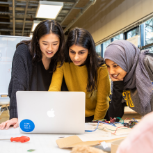 Three students around a computer